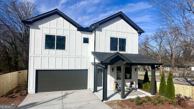 modern farmhouse featuring board and batten siding, fence, a shingled roof, and an attached garage