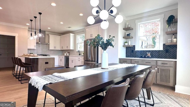 dining space with sink, ornamental molding, and light wood-type flooring