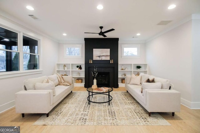 living room with ornamental molding, ceiling fan, a fireplace, and light wood-type flooring