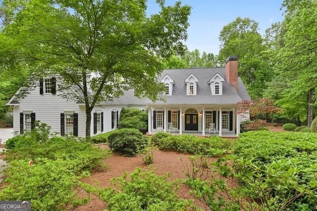 cape cod-style house with a porch and a chimney