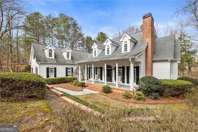 view of front of home featuring covered porch, a shingled roof, and a chimney