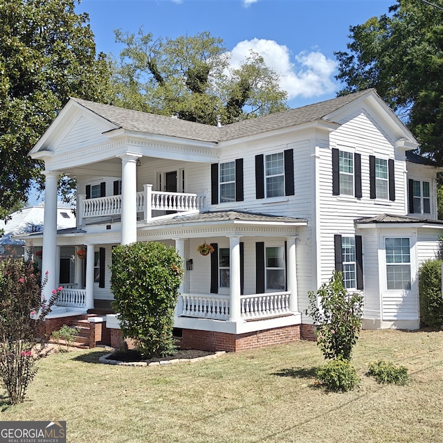 greek revival inspired property with a porch, a balcony, and a front yard