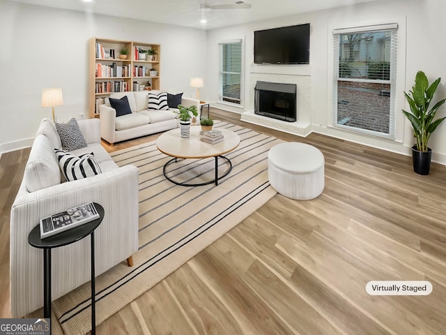 unfurnished living room featuring ceiling fan, wood-type flooring, and a brick fireplace