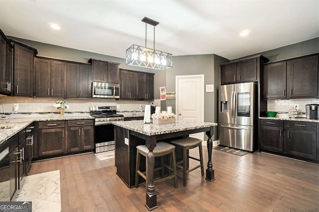 kitchen with appliances with stainless steel finishes, decorative light fixtures, a center island, and dark brown cabinets