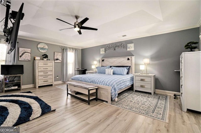 bedroom featuring crown molding, light hardwood / wood-style floors, a raised ceiling, and ceiling fan