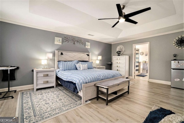 bedroom featuring ornamental molding, wood-type flooring, and a tray ceiling