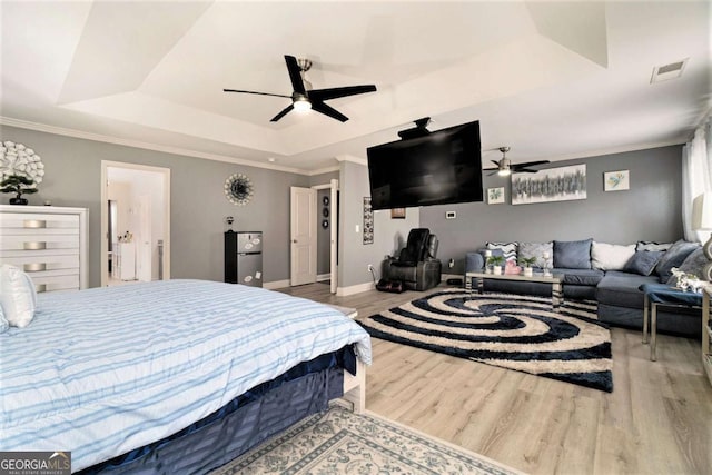 bedroom with hardwood / wood-style flooring, ceiling fan, ornamental molding, and a tray ceiling