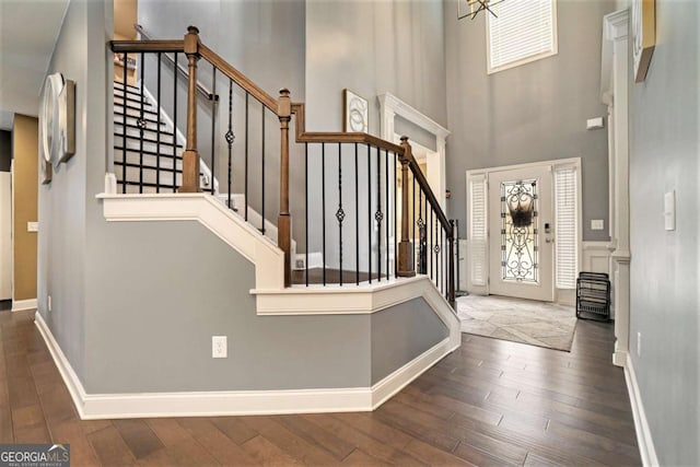 foyer entrance with a towering ceiling and dark hardwood / wood-style floors