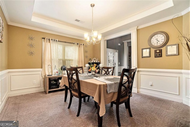 dining space with an inviting chandelier, ornamental molding, a tray ceiling, and carpet