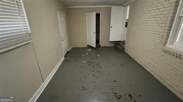 spare room with brick wall and concrete flooring