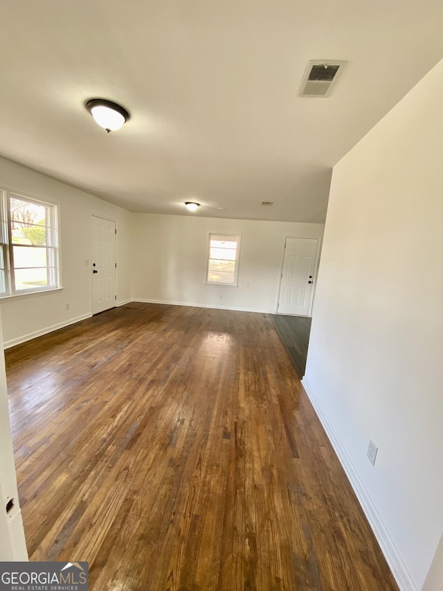 empty room with dark wood-type flooring and a healthy amount of sunlight