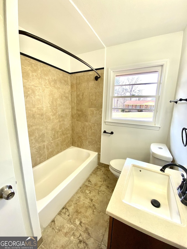 full bathroom featuring tiled shower / bath, vanity, and toilet