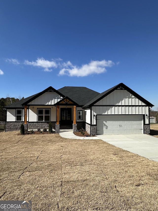 view of front facade featuring driveway, stone siding, an attached garage, and board and batten siding