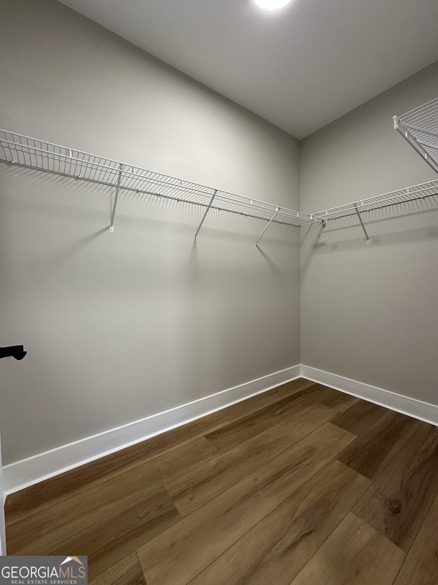 empty room with baseboards, visible vents, a raised ceiling, and wood finished floors