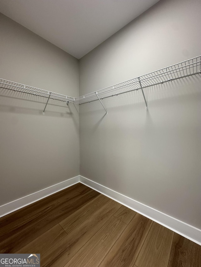 full bathroom featuring marble finish floor, a shower stall, a spacious closet, and a sink