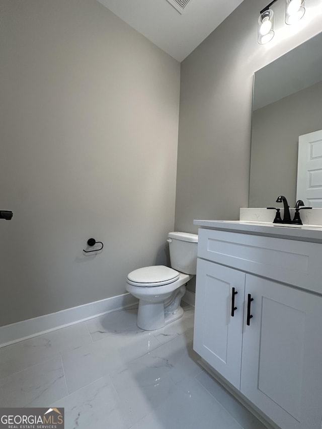 half bathroom featuring baseboards, visible vents, toilet, marble finish floor, and vanity