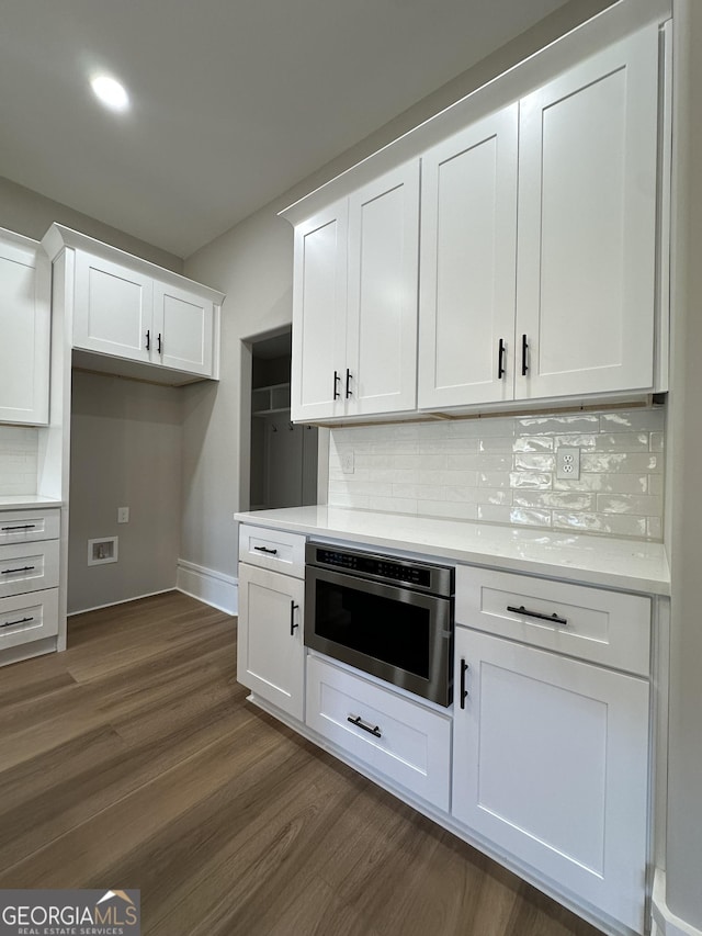 kitchen featuring pendant lighting, white cabinetry, wall chimney range hood, an island with sink, and stainless steel range with electric stovetop