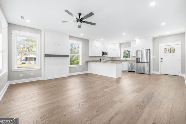 kitchen featuring white cabinetry, light stone counters, kitchen peninsula, stainless steel appliances, and light hardwood / wood-style floors