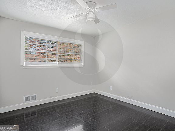 spare room featuring ceiling fan, wood-type flooring, and a textured ceiling