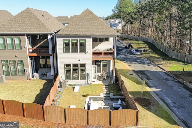 back of house featuring a balcony and a yard