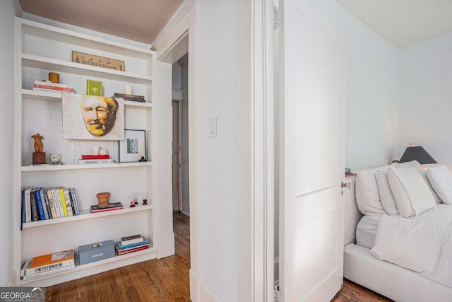 corridor with dark wood-type flooring and built in shelves