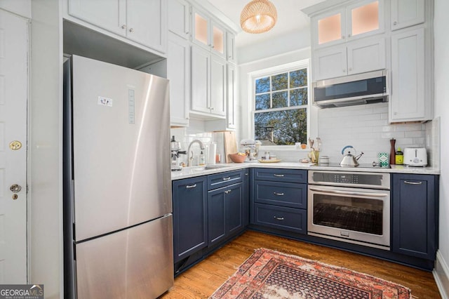 kitchen featuring blue cabinets, sink, white cabinetry, dark hardwood / wood-style flooring, and stainless steel appliances