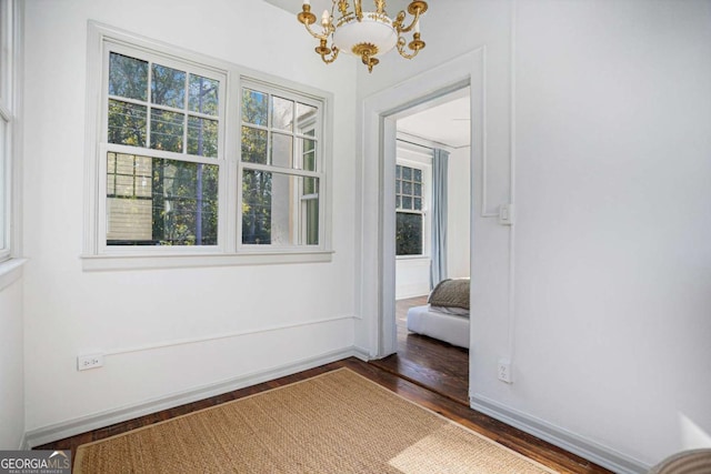 empty room with dark hardwood / wood-style floors and a notable chandelier