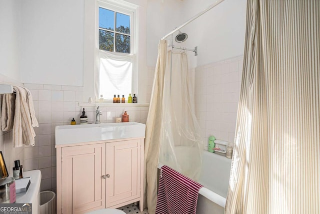 bathroom with tile walls, sink, and shower / tub combo with curtain