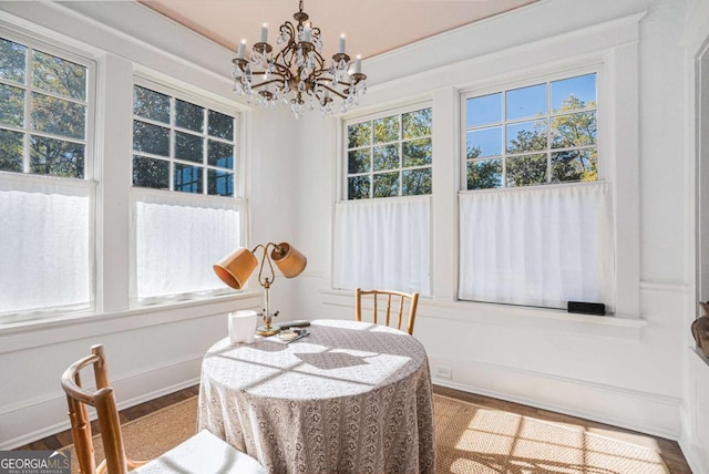 dining area with wood-type flooring, plenty of natural light, and an inviting chandelier