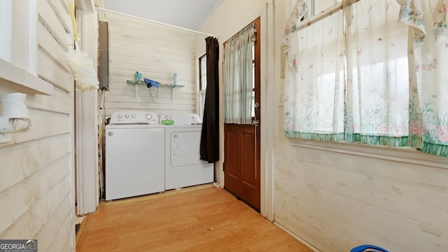 laundry room with independent washer and dryer, wooden walls, and light hardwood / wood-style floors