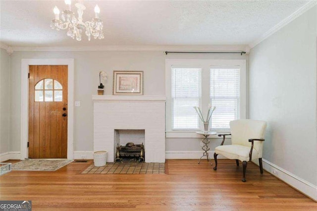 entrance foyer featuring a fireplace, hardwood / wood-style flooring, a notable chandelier, crown molding, and a textured ceiling