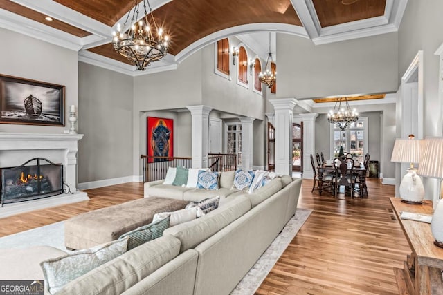 living room with an inviting chandelier, wood-type flooring, ornamental molding, and ornate columns