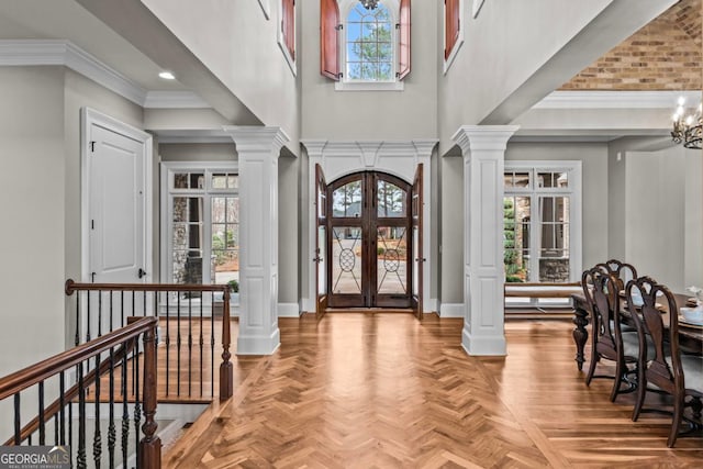 foyer featuring ornate columns, light parquet flooring, and french doors