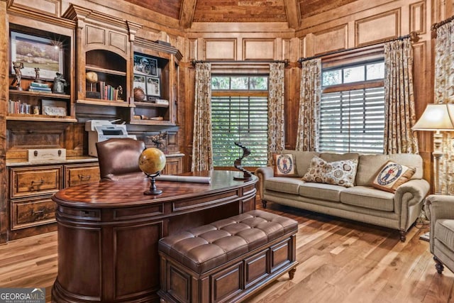 home office with light wood-type flooring and wood walls