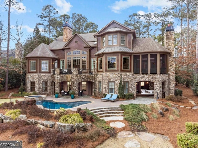 back of property featuring a swimming pool with hot tub, a sunroom, and a patio area