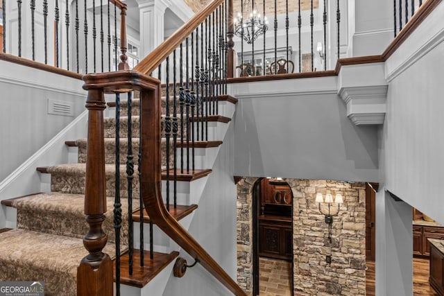 stairway with a towering ceiling and a chandelier