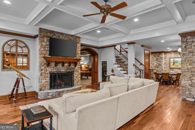 living room with coffered ceiling, crown molding, wood-type flooring, beamed ceiling, and a fireplace