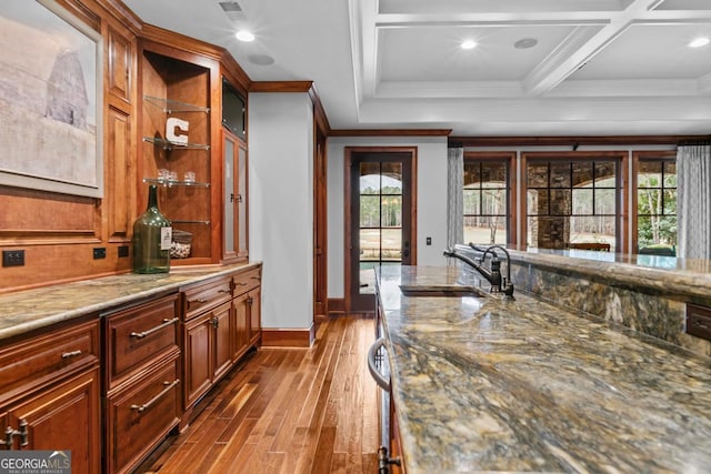 bar with light stone counters, plenty of natural light, sink, and hardwood / wood-style floors