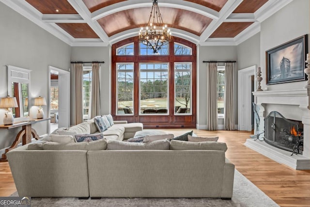 living room with beamed ceiling, coffered ceiling, a chandelier, and light hardwood / wood-style flooring