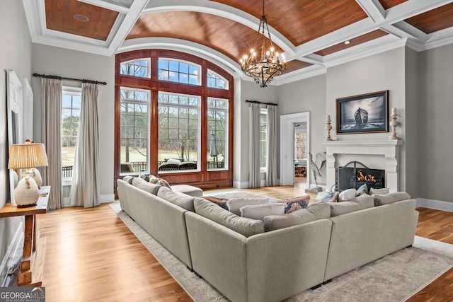 living room featuring beamed ceiling, a notable chandelier, coffered ceiling, and light wood-type flooring