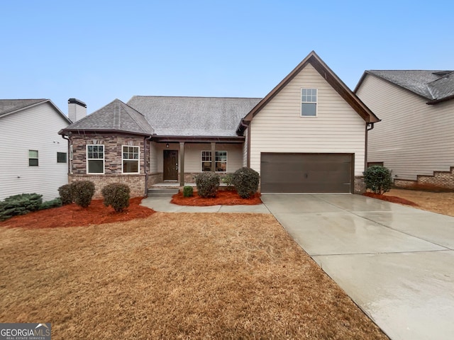 view of front of home featuring an attached garage, concrete driveway, a shingled roof, and stone siding