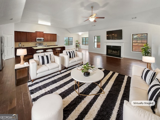 living room with lofted ceiling, dark wood-style flooring, a fireplace, visible vents, and a ceiling fan