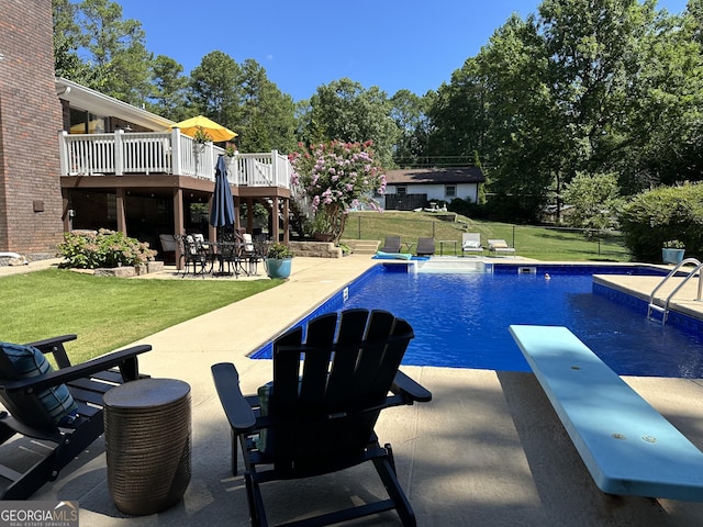 outdoor pool featuring a patio area, a yard, a deck, and a diving board