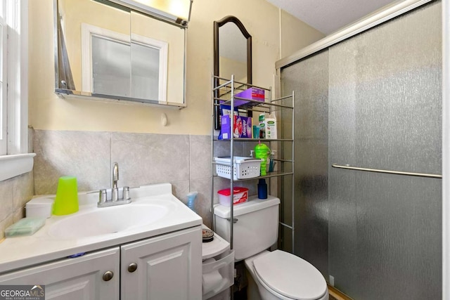 bathroom with tile walls, vanity, an enclosed shower, tasteful backsplash, and toilet