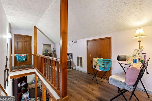 hallway featuring vaulted ceiling, dark wood-type flooring, and a textured ceiling