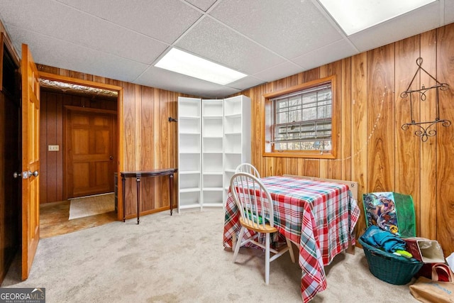 carpeted bedroom featuring a paneled ceiling and wood walls