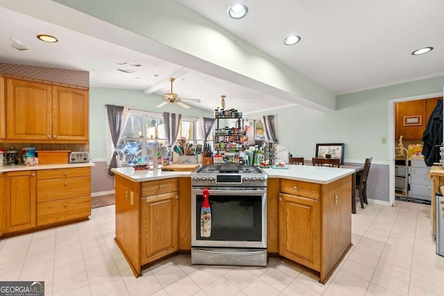 kitchen featuring vaulted ceiling with beams, stainless steel range with gas stovetop, ceiling fan, and a center island