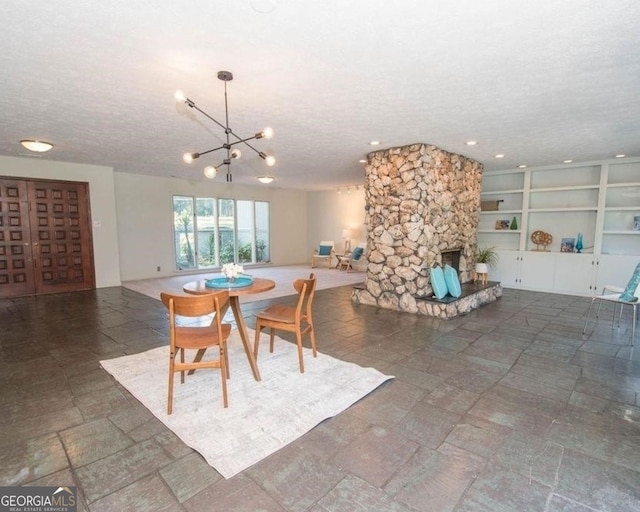 dining area with built in shelves, a notable chandelier, a fireplace, and a textured ceiling