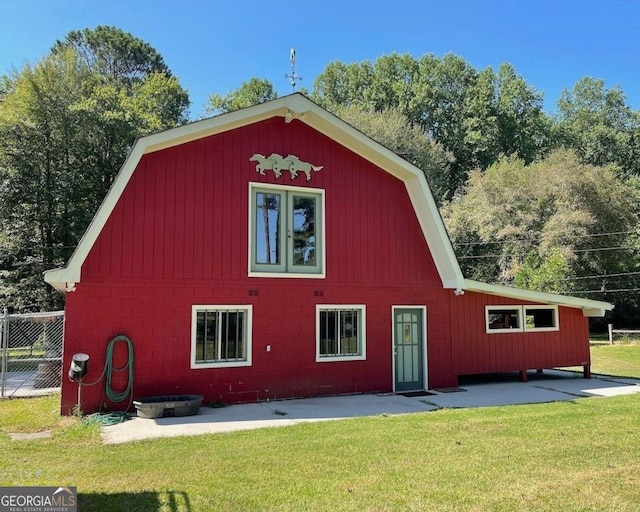 view of barn featuring fence and a lawn