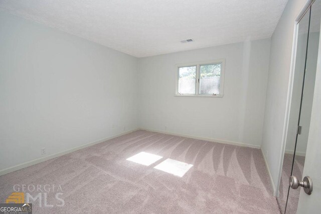 carpeted empty room featuring baseboards, a textured ceiling, and visible vents